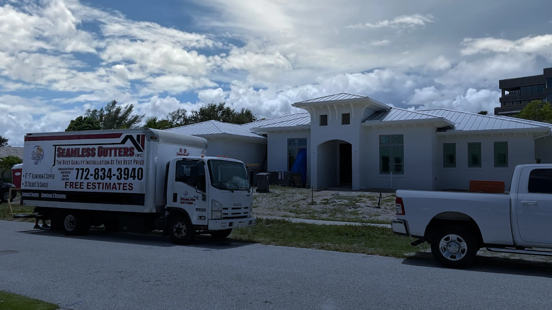 white house with a patio and two white vans outside on a driveway